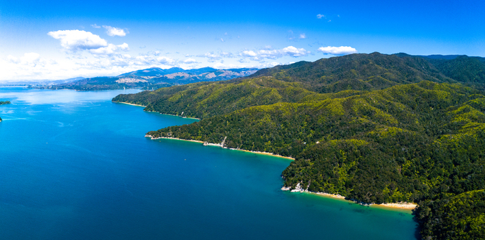 Aerial view of the lush green forests meeting the vibrant blue waters along the Abel Tasman Coastline Abel Tasman National Park Tasman Region New Zealand. Aerial view of the lush green forests meeting the vibrant blue waters along the Abel Tasman Coastline Abel Tasman National Park Tasman Region New Zealand.