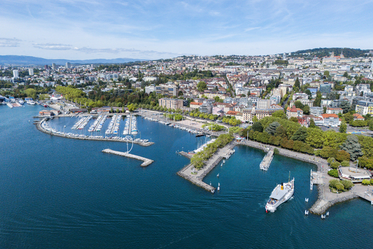 Aerial view of Ouchy Olympique harbor with boats a passenger ferry and the cityscape of Lausanne Vaud Switzerland. Aerial view of Ouchy Olympique harbor with boats a passenger ferry and the cityscape of Lausanne Vaud Switzerland.