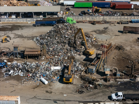 Aerial view of a scrap metal recycling yard with large piles of metal heavy machinery excavators and trucks in Carson California United States.