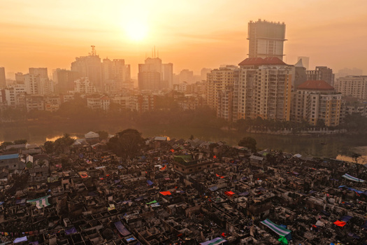 Aerial view of the dense Korail Basti informal settlement with makeshift structures and narrow alleys contrasted against the modern high rise skyline of Dhaka Dhaka Division Bangladesh.