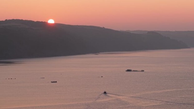 Aerial view of sunrise over the coast and a small boat United Kingdom. Aerial view of sunrise over the coast and a small boat United Kingdom.