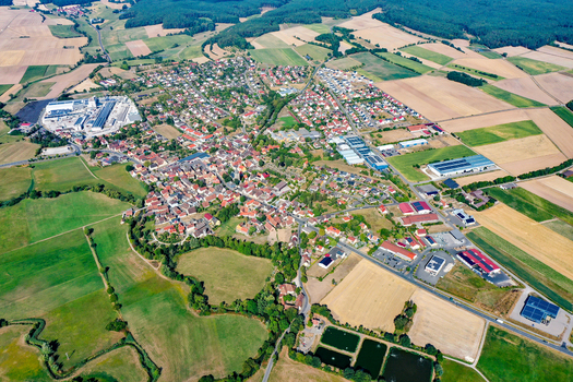 Aerial view of the town of Uehlfeld with its red roofed houses surrounded by vast agricultural fields and lush green forests under a clear sky in Uehlfeld Bavaria Germany. Aerial view of the town of Uehlfeld with its red roofed houses surrounded by vast agricultural fields and lush green forests under a clear sky in Uehlfeld Bavaria Germany.