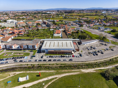 Aerial view of a building with a large parking lot surrounded by houses and green fields in Espinho Portugal. Aerial view of a building with a large parking lot surrounded by houses and green fields in Espinho Portugal.
