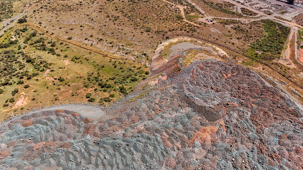 Aerial view of a vast multi hued mine dump its textured grey and reddish strata contrasting with the arid sparse land Rustenburg North West South Africa. Aerial view of a vast multi hued mine dump its textured grey and reddish strata contrasting with the arid sparse land Rustenburg North West South Africa.