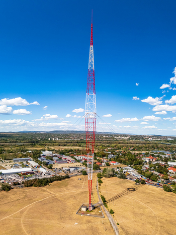 Aerial view of the Lakihegy radio tower a tall red and white lattice mast with guy wires standing in a field near the town of Szigetszentmiklos Pest County Hungary. Aerial view of the Lakihegy radio tower a tall red and white lattice mast with guy wires standing in a field near the town of Szigetszentmiklos Pest County Hungary.