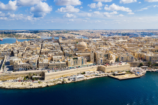 Aerial view of the Basilica of Our Lady of Mount Carmel rising above historic limestone buildings and fortifications with the blue Grand Harbour Valletta Port Region Malta. Aerial view of the Basilica of Our Lady of Mount Carmel rising above historic limestone buildings and fortifications with the blue Grand Harbour Valletta Port Region Malta.