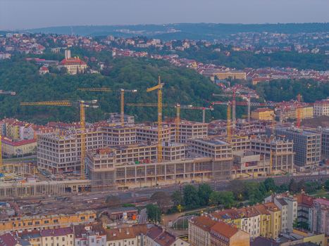 Aerial view of a large construction site featuring multiple yellow tower cranes concrete frameworks and scaffolding set against the urban landscape of Prague Prague Czechia.
