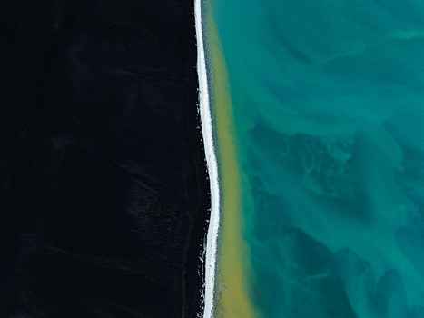 Aerial view of a black sand beach meeting turquoise glacial water in Iceland. Aerial view of a black sand beach meeting turquoise glacial water in Iceland.