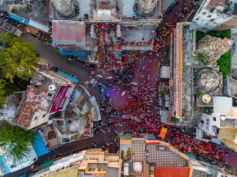 Aerial view of the bustling Jagdish Temple area filled with crowds of people in colorful clothing surrounded by historic stone architecture and urban rooftops in Udaipur Rajasthan India.