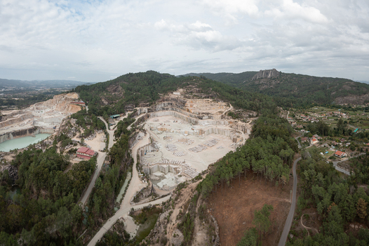 Aerial view of Cantera Porrino showing the extensive granite extraction site with terraced rock faces industrial machinery and surrounding pine forests in O Porrino Pontevedra Spain. Aerial view of Cantera Porrino showing the extensive granite extraction site with terraced rock faces industrial machinery and surrounding pine forests in O Porrino Pontevedra Spain.