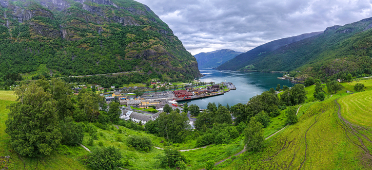 Aerial view of the village of Flam nestled along the Aurlandsfjord surrounded by steep green mountains lush meadows and a harbor in Flam Vestland Norway. Aerial view of the village of Flam nestled along the Aurlandsfjord surrounded by steep green mountains lush meadows and a harbor in Flam Vestland Norway.