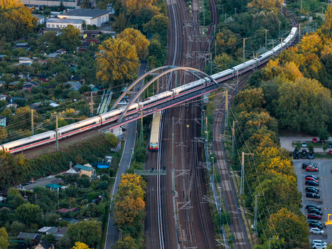 Aerial view of the Ostkreuz railway station in Berlin featuring the arched bridge with a train crossing tracks surrounded by trees and urban infrastructure in Berlin Berlin Germany. Aerial view of the Ostkreuz railway station in Berlin featuring the arched bridge with a train crossing tracks surrounded by trees and urban infrastructure in Berlin Berlin Germany.