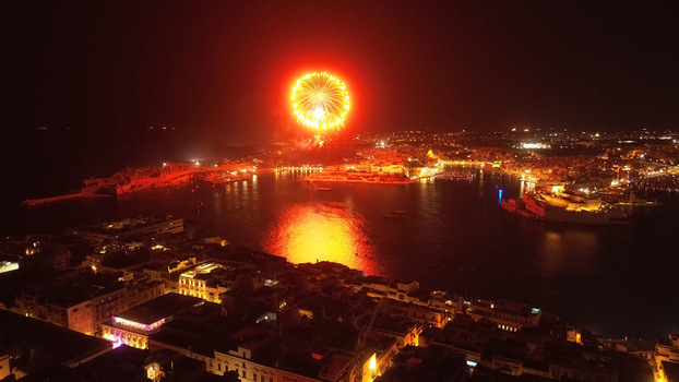 Aerial view of fireworks illuminating the night sky over the harbor with city lights reflecting on the water in Valletta Port Region Malta. Aerial view of fireworks illuminating the night sky over the harbor with city lights reflecting on the water in Valletta Port Region Malta.