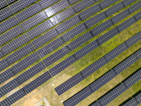 Aerial view of a large solar panel array with rows of photovoltaic modules installed on green grass in Guanaja Bay Islands Department Honduras.