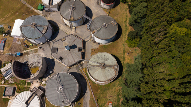 Aerial view of industrial storage tanks and circular structures at a facility surrounded by lush green trees in Milan Lombardy Italy. Aerial view of industrial storage tanks and circular structures at a facility surrounded by lush green trees in Milan Lombardy Italy.