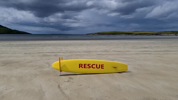 View of a yellow rescue surfboard on a beach in Ireland.