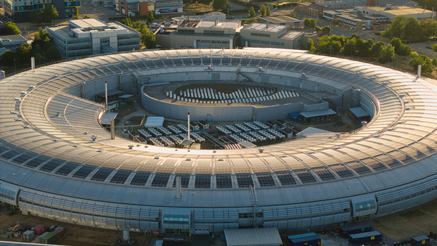 Aerial view of Diamond Light Source a circular synchrotron facility surrounded by greenery under golden hour light in Didcot United Kingdom.