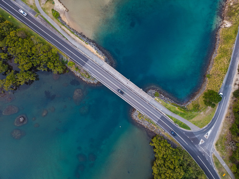 Aerial view of Cudgen Creek with a bridge crossing the turquoise water surrounded by lush mangroves and coastal vegetation in Tweed Shire Council New South Wales Australia.
