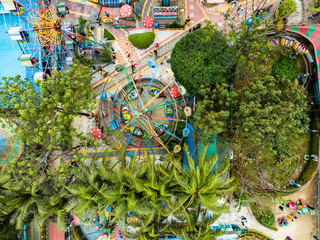 Aerial view of an amusement park featuring a colorful ferris wheel and swing ride surrounded by lush green trees and pedestrian pathways in Dhaka Dhaka Division Bangladesh. Aerial view of an amusement park featuring a colorful ferris wheel and swing ride surrounded by lush green trees and pedestrian pathways in Dhaka Dhaka Division Bangladesh.