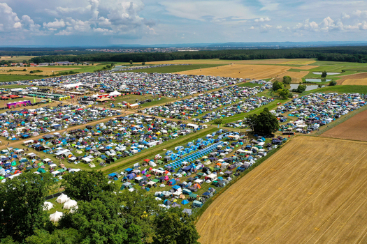 Aerial view of Open Beatz Festival campsite with thousands of colorful tents spread across green fields under a cloudy sky in Herzogenaurach Bayern Germany.