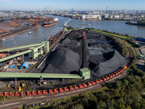 Aerial view of Am Sandauhafen with large coal piles industrial conveyor systems and freight trains along the harbor in Hamburg Germany. Aerial view of Am Sandauhafen with large coal piles industrial conveyor systems and freight trains along the harbor in Hamburg Germany.
