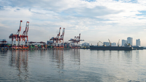View of the Cebu Port Authority with container cranes a cargo ship docked at the pier and the city skyline under a soft morning sky in Cebu City Central Visayas Philippines. View of the Cebu Port Authority with container cranes a cargo ship docked at the pier and the city skyline under a soft morning sky in Cebu City Central Visayas Philippines.