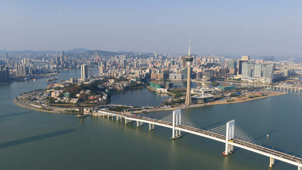 Aerial view of the Macau Tower and Sai Van Bridge spanning across the water with the dense urban skyline under a clear sky in Macau Macao. Aerial view of the Macau Tower and Sai Van Bridge spanning across the water with the dense urban skyline under a clear sky in Macau Macao.