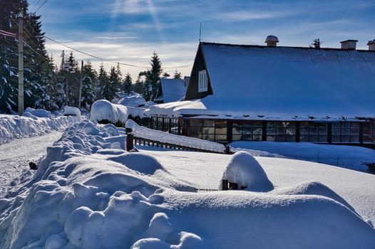 View of a snow laden landscape with buildings and trees under a bright sunny sky casting long shadows across the pristine white blanket Donovaly Slovakia. View of a snow laden landscape with buildings and trees under a bright sunny sky casting long shadows across the pristine white blanket Donovaly Slovakia.