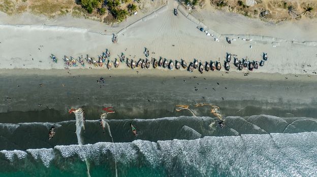Aerial view of boats lined up on the sandy beach with gentle waves lapping the shore creating a mesmerizing contrast of textures and tones Cox s Bazar Chittagong Division Bangladesh. Aerial view of boats lined up on the sandy beach with gentle waves lapping the shore creating a mesmerizing contrast of textures and tones Cox s Bazar Chittagong Division Bangladesh.