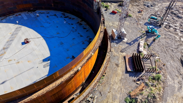 Aerial view of the assembly of a large refinery oil storage tank with metal walls and interior floor under construction at a site with excavators in Kovin Vojvodina Serbia. Aerial view of the assembly of a large refinery oil storage tank with metal walls and interior floor under construction at a site with excavators in Kovin Vojvodina Serbia.
