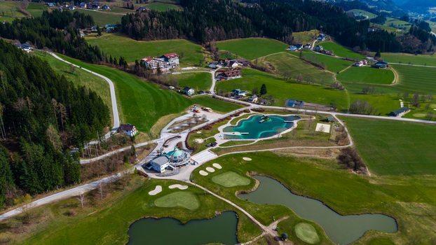 Aerial view of a vibrant green landscape dotted with buildings a golf course and a distinctive blue waterpark contrasting against the lush scenery Windischgarsten Upper Austria Austria. Aerial view of a vibrant green landscape dotted with buildings a golf course and a distinctive blue waterpark contrasting against the lush scenery Windischgarsten Upper Austria Austria.