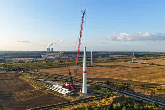 Aerial view of wind turbine construction with a large crane turbine components and the Schleenhain lignite open cast mine in the background near Zwenkau Saxony Germany.