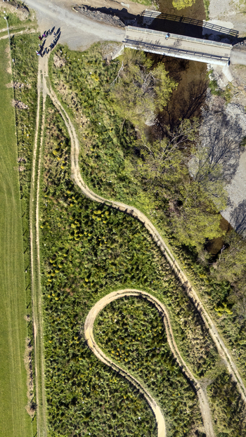 Aerial view of restored wetlands featuring a winding dirt path a small bridge over a stream and lush vegetation in Cable Bay Nelson Region New Zealand. Aerial view of restored wetlands featuring a winding dirt path a small bridge over a stream and lush vegetation in Cable Bay Nelson Region New Zealand.