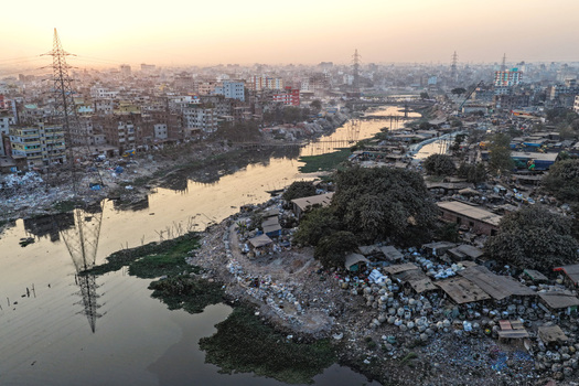 Aerial view of the Buriganga River flowing through dense urban settlements with power lines and sunset light in Dhaka Dhaka Division Bangladesh. Aerial view of the Buriganga River flowing through dense urban settlements with power lines and sunset light in Dhaka Dhaka Division Bangladesh.