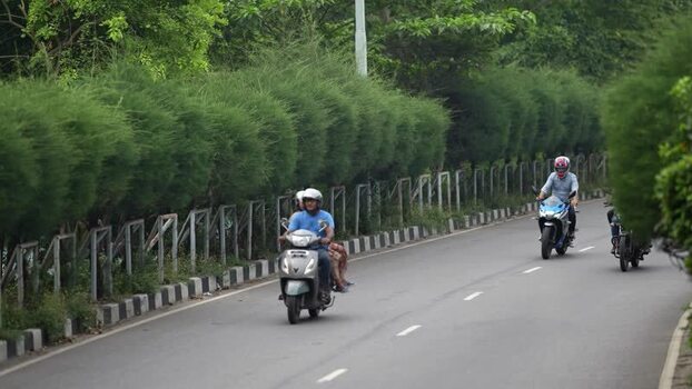 View of motorcyclists riding on a road with green bushes Bangladesh.