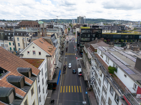 Aerial view of urban rooftops and a main street with crosswalks and traffic under a cloudy sky in Biel Bienne Canton of Bern Switzerland. Aerial view of urban rooftops and a main street with crosswalks and traffic under a cloudy sky in Biel Bienne Canton of Bern Switzerland.