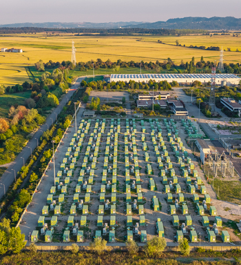 Aerial view of a battery energy storage system with rows of green containers industrial facility and surrounding agricultural fields in Trino Piedmont Italy.