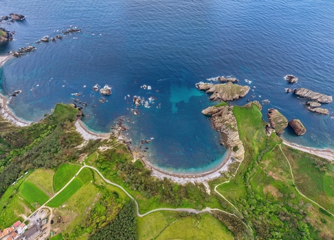 Aerial view of the horseshoe shaped bay with turquoise water rocky cliffs and lush green fields in Cudillero Asturias Spain. Aerial view of the horseshoe shaped bay with turquoise water rocky cliffs and lush green fields in Cudillero Asturias Spain.