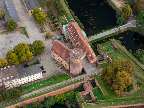 Aerial view of Spandau Citadel featuring its historic brick tower surrounding fortifications moat and lush green trees in Berlin Berlin Germany.