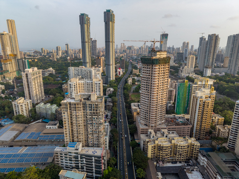 Aerial view of the dense urban skyline featuring modern high rise residential towers construction sites with cranes and a busy road in Mumbai Maharashtra India. Aerial view of the dense urban skyline featuring modern high rise residential towers construction sites with cranes and a busy road in Mumbai Maharashtra India.