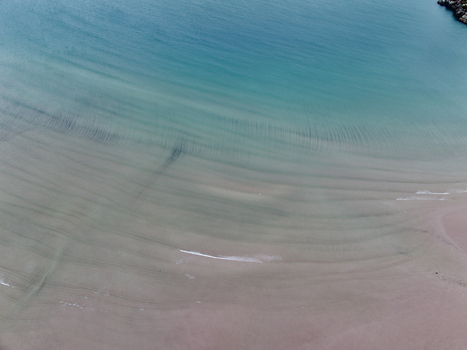 Aerial view of Gruinard Bay featuring turquoise water gentle waves and sand ripples on the shore in Gruinard Scotland United Kingdom. Aerial view of Gruinard Bay featuring turquoise water gentle waves and sand ripples on the shore in Gruinard Scotland United Kingdom.