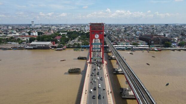 Aerial view of the iconic red Ampera Bridge spanning the Musi River with traffic flowing across surrounded by the urban cityscape of Palembang Sumatera Selatan Indonesia. Aerial view of the iconic red Ampera Bridge spanning the Musi River with traffic flowing across surrounded by the urban cityscape of Palembang Sumatera Selatan Indonesia.