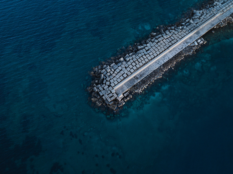 Aerial view of the concrete block breakwater protecting the Island of Ortigia coastline surrounded by deep blue Mediterranean waters in Syracuse Sicily Italy. Aerial view of the concrete block breakwater protecting the Island of Ortigia coastline surrounded by deep blue Mediterranean waters in Syracuse Sicily Italy.