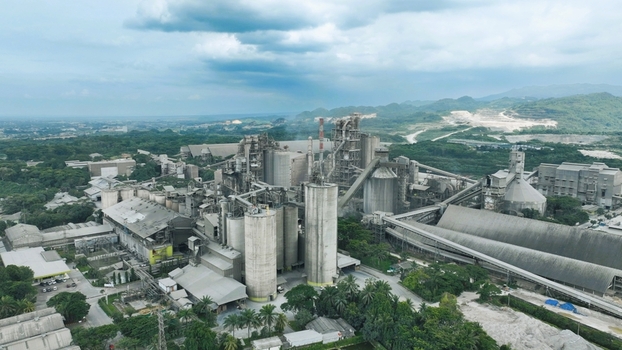 Aerial view of the Nambo cement factory in Klapanunggal featuring industrial silos conveyor belts and processing buildings surrounded by greenery in Klapanunggal West Java Indonesia. Aerial view of the Nambo cement factory in Klapanunggal featuring industrial silos conveyor belts and processing buildings surrounded by greenery in Klapanunggal West Java Indonesia.
