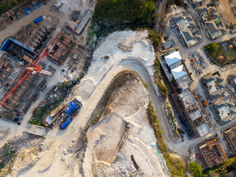 Aerial view of a resort development site featuring construction cranes unfinished building structures and cleared land in Kecamatan Kuta Selatan Bali Indonesia. Aerial view of a resort development site featuring construction cranes unfinished building structures and cleared land in Kecamatan Kuta Selatan Bali Indonesia.