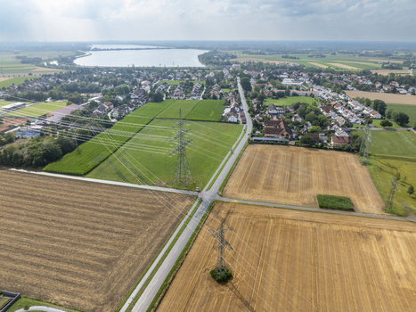 Aerial view of Neufinsing reservoir surrounded by agricultural fields power lines and residential houses in Finsing Bayern Germany.