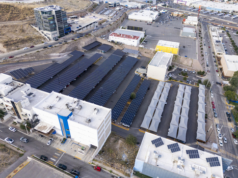 Aerial view of a large parking lot covered with solar panel arrays in an urban setting with surrounding buildings and roads in Chihuahua Chihuahua Mexico. Aerial view of a large parking lot covered with solar panel arrays in an urban setting with surrounding buildings and roads in Chihuahua Chihuahua Mexico.