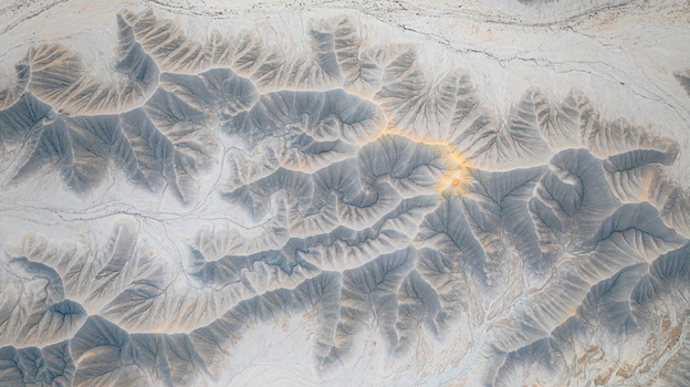 Aerial view of the intricate eroded ridges and deep gullies of the badlands showcasing stark contrast between light clay and dark weathered slopes in Hanksville Utah United States.