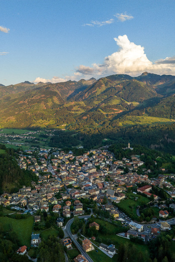 Aerial view of Fiemme Valley featuring a charming town nestled among lush green mountains dense forests and rolling meadows Trentino Alto Adige Italy.