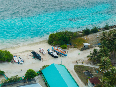 Aerial view of boats resting on the sandy shore where the turquoise water meets the land Vashafaru Island Thiladhummathi Atoll Maldives. Aerial view of boats resting on the sandy shore where the turquoise water meets the land Vashafaru Island Thiladhummathi Atoll Maldives.